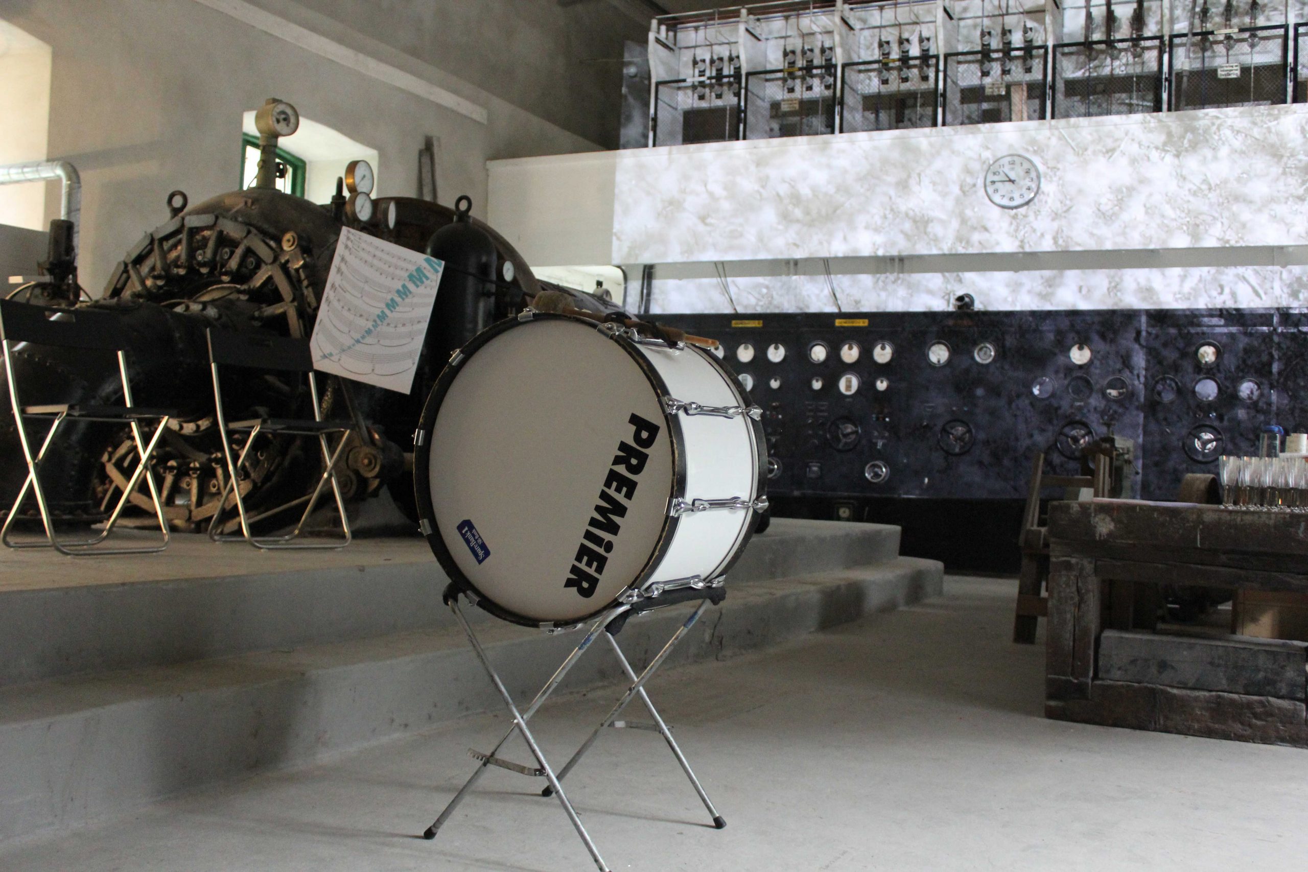 a bass drum on a stand in a room with a projection and equipment in the background