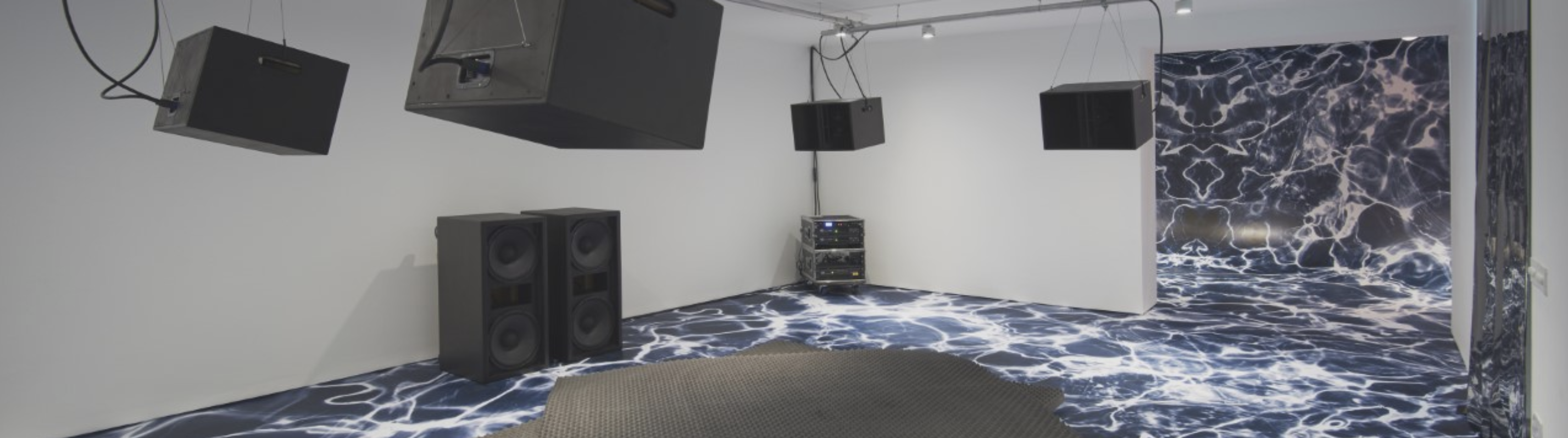 An art installation with speakers and a blue and white floor and wall covering