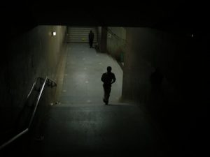 CCTV photograph showing a person walking up a set of stairs in dim lighting