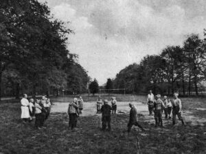 A playing field with football goal posts - a group of people play standing in a circle