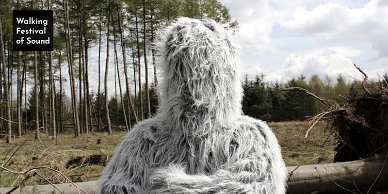 A person in a grey / white fluffy suit in front of trees