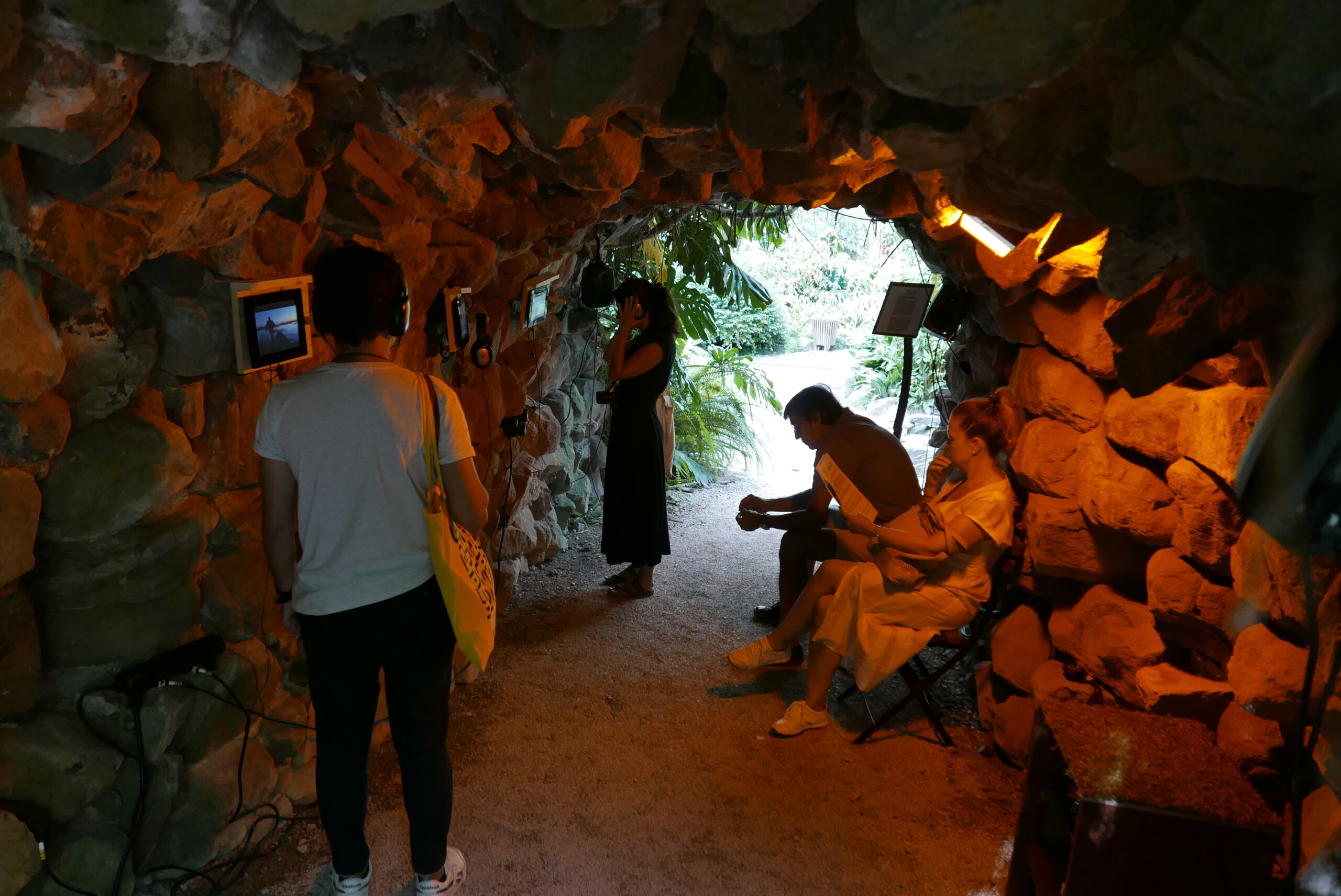 Installation of Aral Sea - a cave with three people listening on headpones, watching wall mounted ipads