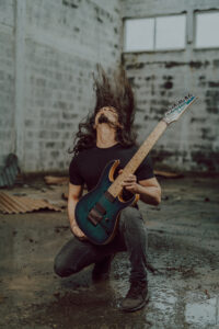berk kneeling with a guitar, flicking his head and hair back in an arch