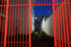 a red fence into a residential courtyard by night